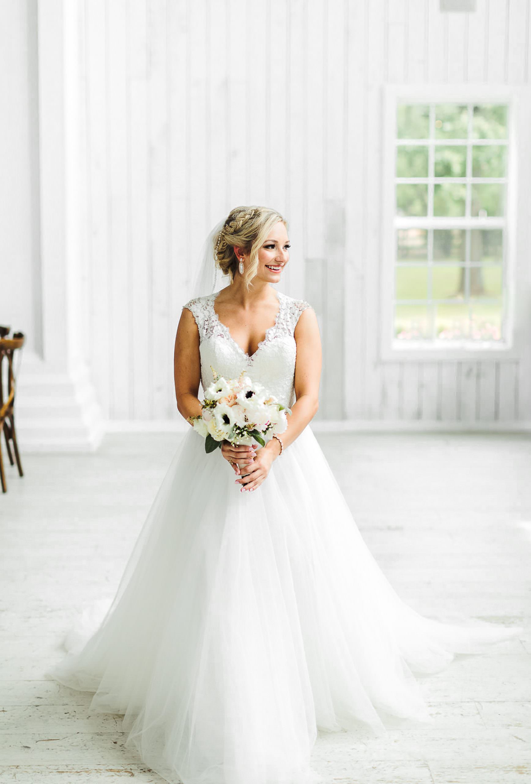 bride holding a bouquet of flowers looking out the window at Fort Worth Wedding Venues